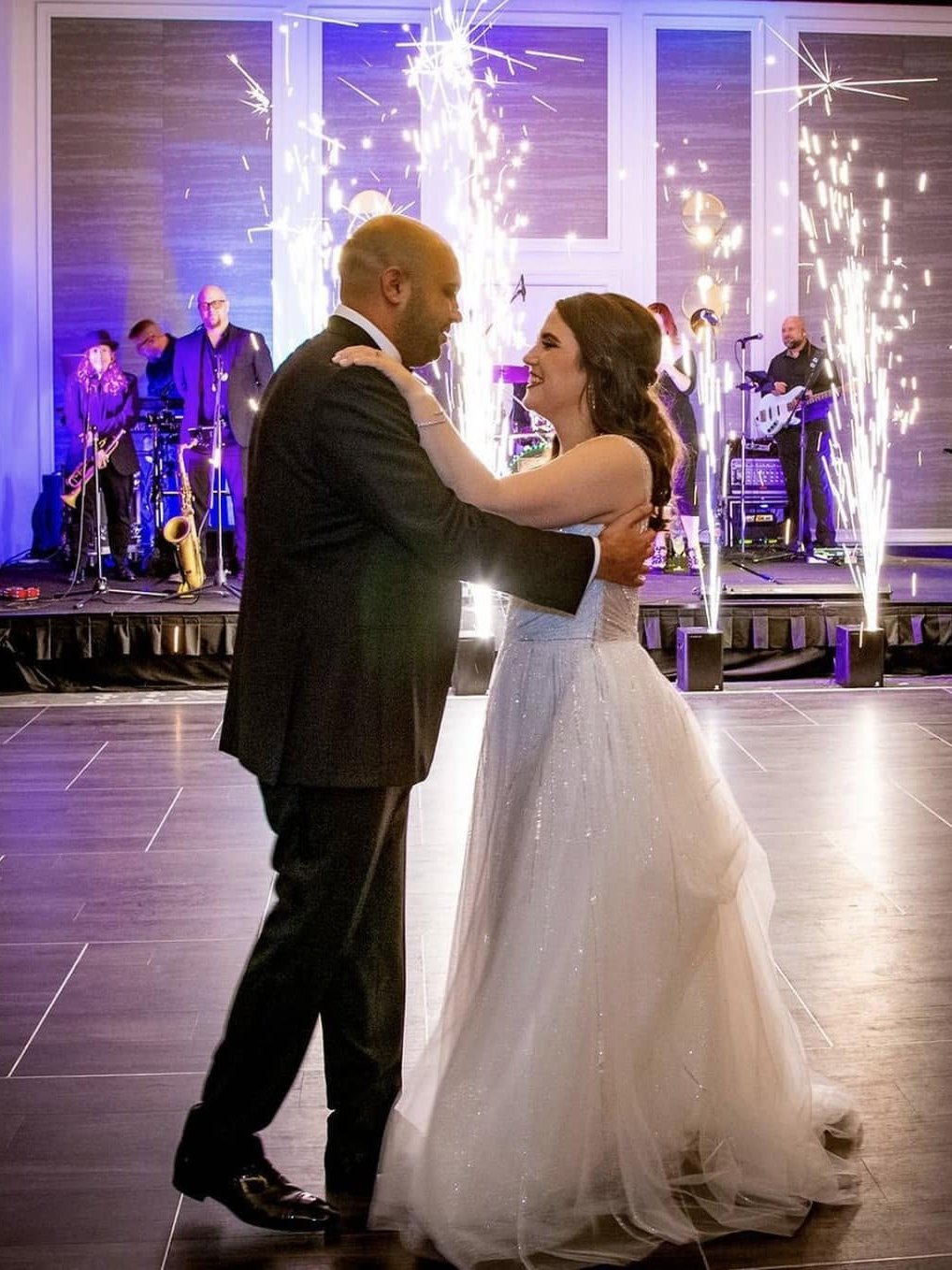 A wedding first dance with sparkler fountains and Sugar Shaker performing behind